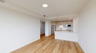 Located at 2140 North Lincoln Park West in Chicago's coveted Lincoln Park neighborhood, this thoughtfully designed one-bedroom, one-bathroom residence offers a clean, modern aesthetic throughout. Light hardwood flooring runs continuously across the entire space, creating a cohesive and airy feel.

The open-concept kitchen and living area serves as the heart of the home. The kitchen is well-appointed with shaker-style cabinetry in a warm taupe finish, white quartz countertops, a subway tile backsplash, stainless steel appliances including a full-size refrigerator and dishwasher, and a peninsula that provides additional prep space and a natural divide from the living area. Recessed lighting illuminates the kitchen efficiently.

A bright hallway with recessed lighting connects the living area to the private quarters. The bedroom is a comfortable retreat, featuring a large picture window that frames outdoor views of the surrounding neighborhood and fills the room with natural light. A spacious closet with built-in shelving provides ample storage, complemented by a secondary closet with a sliding barn-style door.

The bathroom showcases a sleek, glass-enclosed walk-in shower with textured white tile walls, geometric mosaic floor tile in charcoal tones, and matte black fixtures, delivering a refined, spa-like finish.
