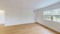 Located at Westridge Gardens in Phoenixville, PA, this one-bedroom, one-bathroom residence offers a thoughtfully designed single-floor layout with approximately 820 square feet of living space. The open-concept kitchen and living area serves as the heart of the home, featuring warm hardwood-style flooring, crisp white walls, and abundant natural light from multiple windows. The kitchen is well-appointed with gray shaker-style cabinetry, dark granite countertops, stainless steel appliances including a refrigerator, range, and microwave, a stainless steel sink, and pendant lighting over a generous island—ideal for both meal preparation and casual dining. The spacious bedroom offers plush carpeting, a large window with views of the surrounding greenery, and a dedicated closet for ample storage. The full bathroom features a soaking tub and shower combination, tile flooring, and a bright window for natural ventilation. A private balcony extends the living space outdoors, offering peaceful views of lush green lawns and mature trees. The community surroundings include well-maintained grounds, mature landscaping, and convenient parking. This residence combines comfortable interiors with a tranquil natural setting.