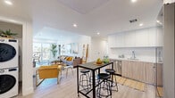 Located at 2600 S Bentley Ave in Los Angeles, this modern residence offers four bedrooms and four bathrooms across a single-floor, open-concept layout. The living area is bright and inviting, featuring recessed lighting, light wood-style flooring, and large sliding glass doors that lead to a private balcony with views of the Los Angeles skyline. The space flows seamlessly into a well-appointed kitchen equipped with stainless steel appliances, flat-front cabinetry in white and warm wood tones, a clean white countertop, and a built-in dining bar with seating — ideal for casual meals or entertaining. Each of the four bedrooms is thoughtfully designed with plush carpeting, recessed lighting, and access to natural light; select rooms open directly onto their own balconies. The primary bedroom is generously proportioned and includes a dedicated closet. The four bathrooms maintain a consistent modern aesthetic, featuring wood-toned vanities, white quartz countertops, large wall mirrors, and clean white tile surrounds with tub-shower combinations or walk-in showers. Every bedroom is served by its own closet, providing excellent storage throughout. The overall ambiance is clean, contemporary, and well-lit, reflecting a refined California-modern sensibility.