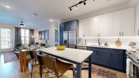 Located at 5180 Peachtree Blvd in Chamblee, GA, this thoughtfully designed 2-bedroom, 2-bathroom residence offers a seamless blend of modern aesthetics and functional living. The open-concept kitchen and living area serves as the heart of the home, showcasing a striking two-tone cabinet design with navy lower cabinets and crisp white uppers, complemented by a white subway tile backsplash, stainless steel appliances, and a central island with seating. Light hardwood flooring flows throughout the main living areas, adding warmth and continuity. The living room features crown molding, a ceiling fan, and large windows with balcony access, filling the space with natural light and outdoor views. The primary bedroom offers a generous footprint with large windows, plush carpeting, and direct access to a well-appointed en-suite bathroom complete with a dual-sink navy vanity and white quartz countertops. The second bedroom provides a versatile space with neutral tones, carpeted floors, and easy access to the hallway. Both bathrooms echo the navy and white design palette, maintaining a cohesive aesthetic. Two closets provide ample storage throughout the residence.