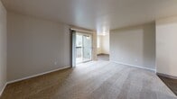 Located at 8660 N Columbia Blvd in Portland, Oregon, this 2-bedroom, 1-bathroom unit offers a well-organized single-level layout designed for comfortable everyday living. The entrance leads into a hallway that connects all areas of the home efficiently. The living room is carpeted and bright, featuring a sliding glass door that opens onto a private balcony overlooking a landscaped green lawn and neighboring multi-story buildings with classic green siding. The galley-style kitchen and dining area are equipped with white cabinetry trimmed in gold hardware, light countertops, wood-look flooring, and white appliances including a range and refrigerator — providing a functional and clean workspace. Both bedrooms are carpeted and feature neutral tones with baseboard heating and natural light from windows. The primary bedroom includes a sliding closet door and additional access to a walk-in style closet area. The unit features a notable four closets total, offering generous storage throughout. The full bathroom includes a single-sink vanity with cabinetry, a large mirror, wood-look flooring, and a tub/shower combination. The overall ambiance is clean, neutral, and move-in ready, with a practical layout suited for individuals or small families.