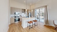 Located at 600 West State Street in Kennett Square, PA, this thoughtfully designed one-bedroom, one-bathroom residence offers a modern aesthetic with high ceilings and light wood flooring throughout. The open-concept layout connects the kitchen, dining, and living areas into a cohesive, airy space filled with natural light from large windows.

The kitchen is a standout feature, showcasing light wood cabinetry, open shelving, a white quartz island with bar seating, stainless steel appliances, and pendant lighting. Glass sliding doors lead directly to a private balcony, seamlessly blending indoor and outdoor living.

The living room is bright and welcoming, with soaring ceilings and multiple windows that frame outdoor views, creating an expansive feel well beyond its footprint. A clean hallway with recessed lighting and framed wall art connects the main living areas to the private spaces.

The bedroom is a serene retreat, featuring plush carpeting, elevated ceilings, and a large window that invites ample natural light. A generously sized walk-in closet with wire shelving provides practical storage. The bathroom is finished with light wood vanity cabinetry, a white countertop, a large mirror, and contemporary lighting fixtures, all set on warm hardwood flooring for a clean, cohesive look.