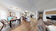 Located at 132 Varsity Dr in Huntsville, Texas, this single-story home offers 4 bedrooms and 3 bathrooms across a well-utilized floor plan. The open-concept common area seamlessly connects the living room, dining area, and kitchen, creating a cohesive and functional space. The living room features wood-look flooring, crown molding, a textured ceiling, and multiple windows that bring in natural light. The kitchen is outfitted with gray shaker-style cabinetry, granite countertops, a mosaic tile backsplash, and stainless steel appliances, including a refrigerator and range. A breakfast bar with bar seating connects the kitchen to the adjacent dining area, which features windows on multiple walls and crown molding. The three bathrooms include tub-shower combos and vanities with white cabinetry. Wood-look flooring runs through the bathrooms as well, maintaining a consistent aesthetic. The four bedrooms each offer a ceiling fan, closet space, and windows for natural light, with individual character in each room. A hallway connects the bedrooms to the main living areas. Throughout the home, textured ceilings and crown molding provide classic detailing, while the consistent wood-look flooring ties all spaces together cohesively.
