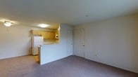 Located at 1614 C Ashby, this single-floor unit offers a practical and well-organized layout designed for everyday living. The open-concept design connects the kitchen and living area seamlessly, creating a sense of spaciousness throughout. The kitchen is equipped with warm honey-toned wood cabinetry, a white refrigerator, and a built-in microwave, with countertops that extend into a peninsula-style breakfast bar — ideal for casual dining or meal prep. The kitchen benefits from overhead flush-mount lighting that keeps the space bright and functional. The living area is finished with plush carpeting in a neutral tone, providing a comfortable and cohesive feel. A paneled entry door with a standard lock is visible, offering straightforward access to the unit. The neutral wall tones throughout create a clean, move-in-ready aesthetic that allows for easy personalization. The overall layout is efficient and thoughtfully arranged, making good use of the available floor space while maintaining an open, airy atmosphere. This unit is well-suited for those seeking a straightforward, single-level living arrangement with key amenities conveniently accessible.