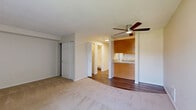 Located at 23207 Pacific Hwy in Edmonds, WA, this efficiently designed unit offers a thoughtful layout across a single floor. The open living area features soft carpeting, neutral walls, and a ceiling fan overhead, creating a comfortable and airy atmosphere. A sliding door leads to a private balcony, allowing natural light to fill the space and offering outdoor views of the surrounding area.

The galley-style kitchen is well-appointed with warm honey-toned wood cabinetry, light granite countertops, and black appliances including a refrigerator, electric range, and dishwasher. Wood-look flooring runs throughout the kitchen and entry areas, providing a clean contrast to the carpeted living space. A pass-through opening connects the kitchen to the main living area, enhancing the sense of openness.

A hallway leads from the living area to the bathroom, which includes a full soaking tub and shower combination with clean white surroundings and chrome fixtures. Closet storage is available within the unit, with sliding panel doors for easy access. The overall design is clean, functional, and well-maintained, making this Edmonds location a practical and comfortable option.