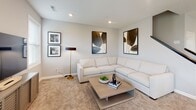 This two-story home offers a thoughtfully designed layout with modern finishes and a neutral color palette that creates a bright, cohesive atmosphere throughout. The main level opens to an airy kitchen equipped with white shaker cabinetry, stainless steel appliances, a large island with bar seating, and pendant lighting overhead. A sliding glass door floods the space with natural light and provides outdoor views. Adjacent to the kitchen, the dining area features light hardwood-style flooring and multiple windows, flowing seamlessly into the living spaces. A convenient half bath is tucked near the entry, finished with tile flooring and clean, simple décor. The upper floor is home to a generously sized primary bedroom with plush carpeting and ample space for a full bedroom suite. A spacious walk-in closet with wire shelving and hanging rods provides abundant storage. The upper-level bathroom features a dual-sink vanity with white quartz countertops and crisp white cabinetry. A cozy lounge area on this level, finished with carpet and accompanied by a staircase, offers a secondary retreat. Additional bedrooms feature carpet, neutral walls, and windows that invite natural light. A dedicated utility area houses the water heater and laundry appliances, rounding out this functional and well-equipped home.