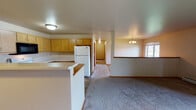 This single-floor residence offers a practical and comfortable layout designed for everyday living. The entryway greets visitors with durable tile flooring and direct access to the main living areas. The open-concept kitchen and dining space are well-appointed with light oak cabinetry offering ample storage, a full suite of appliances including a refrigerator, electric range, built-in microwave, dishwasher, and a double sink. A peninsula counter provides additional workspace and defines the boundary between the kitchen and the adjoining carpeted living and dining areas, which are illuminated by a chandelier. The spacious living room features a corner tile-surround fireplace as a focal point, plush carpeting, a baseboard heating system, and sliding glass patio doors that open to outdoor views and fill the room with natural light. The bedrooms are carpeted and bright, each featuring windows with natural light, baseboard heaters, and ceiling fixtures; one bedroom includes a ceiling fan and a closet with a clothes rod. Two bathrooms serve the home, both finished with tile flooring and baseboard heating, each equipped with a tub-shower combination, toilet, and vanity storage.