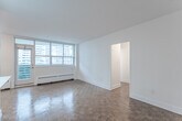 Located on the 15th floor at 85 Redpath Avenue in Toronto's vibrant Midtown neighbourhood, this 2-bedroom, 1-bathroom unit offers a functional and well-appointed layout across a single floor. Warm parquet flooring flows throughout the living areas and bedrooms, adding a classic character to the bright, white interior. The open living and dining area is bathed in natural light from a large floor-to-ceiling window wall, and provides direct access to one of two private balconies, framing impressive city skyline views. A second balcony is accessible from the primary bedroom, which also features a sliding closet and its own window overlooking the cityscape. The second bedroom includes built-in closet storage and a window with views of surrounding towers. The kitchen is clean and efficiently designed with white cabinetry, stainless steel appliances including a full-size refrigerator, and tile backsplash. A bright entryway with vinyl flooring connects the kitchen to the front door. The full bathroom features a soaker tub with overhead shower, white tile surround, and chrome fixtures. Baseboard heating is present throughout, and the unit's crisp white walls complement the warm tones of the parquet floors for a balanced, inviting atmosphere.