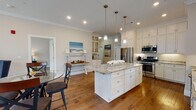 This single-floor residence in South Easton, Massachusetts, is thoughtfully designed with a cohesive aesthetic that blends classic craftsmanship with modern comfort. Crown molding and warm hardwood flooring flow throughout, creating a unified and polished atmosphere.

The kitchen serves as the heart of the home, showcasing white shaker cabinetry extending to the ceiling, granite countertops, and a generously sized central island with pendant lighting overhead. Stainless steel appliances, including a gas range, microwave, and refrigerator, provide full functionality, while a built-in display cabinet adds additional character. Natural light from nearby windows brightens the workspace.

The living area features a white-mantled fireplace with a glowing electric insert, hardwood floors, and large windows that frame views of the surrounding landscape, creating a warm and inviting retreat.

The bedrooms are serene and well-proportioned, each featuring hardwood flooring, ample natural light, and ceiling details that lend a refined finish. The bathrooms are appointed with granite-topped vanities, tile flooring, and a walk-in glass-enclosed shower with white subway tile, reflecting a clean and contemporary sensibility throughout.