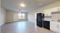 This contemporary 1-bedroom apartment in Bettendorf, Iowa, offers 650 square feet of thoughtfully designed living space. The open-concept floor plan seamlessly integrates the kitchen and living area, creating a spacious feel. The kitchen boasts modern white cabinetry, sleek black appliances, and ample counter space, perfect for culinary enthusiasts. The living room features wood-look flooring and large windows that flood the space with natural light. The bedroom, measuring 130 square feet, provides a cozy retreat with plush carpeting and generous closet space. The bathroom showcases a modern design with a combined tub and shower. Additional amenities include an in-unit laundry area and ceiling fans throughout. The neutral color palette and clean lines create a versatile canvas for various decor styles, while the overall design prioritizes functionality and comfort in this compact yet efficient living space.