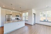 Located at 191 Commerce Dr in Villa Rica, GA, this well-appointed 2-bedroom, 2-bathroom single-story residence offers a thoughtfully designed open-concept layout with modern finishes throughout. The combined kitchen and living area serves as the heart of the home, showcasing light wood-tone cabinetry, granite countertops, a subway tile backsplash, and a central island with a built-in sink. Stainless steel appliances, including a refrigerator, microwave, and gas range, complete the kitchen, while stylish pendant lighting adds a contemporary touch. Durable wood-look flooring extends throughout the main living areas, complemented by recessed lighting and large windows that invite abundant natural light and outdoor views. A clean, well-lit hallway with panel-style gray doors connects the bedrooms and bathrooms. The bedrooms feature plush carpeting, ceiling fans, and windows overlooking the outdoors. The primary bedroom includes a spacious walk-in closet outfitted with wire shelving for generous storage. The bathrooms are finished with tiled tub-shower combinations and wood-look flooring. Clean white walls and neutral tones throughout create a bright, cohesive ambiance ideal for comfortable everyday living.