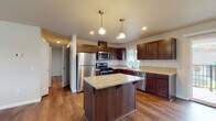 This single-floor residence offers a thoughtfully designed layout that balances functionality with modern style. The kitchen serves as the centerpiece of the home, showcasing rich dark wood cabinetry, light granite countertops, a central island with pendant lighting overhead, and a full suite of stainless steel appliances including a gas range, microwave, dishwasher, and refrigerator. Warm hardwood-style flooring flows seamlessly throughout the main living areas, adding continuity and warmth to the space. The open-concept design connects the kitchen directly to the living area, which benefits from abundant natural light and sliding glass door access to an outdoor patio. Bedrooms feature plush carpeting and windows that bring in natural light, offering a comfortable and quiet retreat. The bathrooms are finished with dark wood vanities, hardwood-style flooring, and clean white fixtures, with at least one bathroom featuring a walk-in glass-enclosed shower and another offering a full tub. The neutral color palette throughout the home creates a clean, inviting atmosphere well-suited for a variety of furnishing styles. Recessed lighting and a wall-mounted HVAC unit round out the practical features of this move-in ready residence.