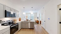 Located at 700 E. Long St. in Columbus, Ohio, this two-bedroom, one-bathroom unit offers a thoughtfully designed single-floor layout that makes efficient use of its space. Light-toned hardwood flooring runs throughout, connecting each room with a clean, cohesive aesthetic.

The living room is bright and welcoming, featuring large double-pane windows with blinds that flood the space with natural light. The kitchen is well-appointed with gray shaker-style cabinetry, white countertops, a classic subway tile backsplash, and stainless steel appliances including a refrigerator, range, and over-the-range microwave.

The primary bedroom benefits from generous window coverage that brings in ample natural light, while the second bedroom offers a similarly airy feel with its own large windows. Both rooms feature clean white walls that complement the warm flooring.

The bathroom is finished in a contemporary style with a deep green vanity, black hardware accents, light wood flooring, and framed wall art that adds character. A hallway with built-in open shelving provides convenient additional storage, while the well-proportioned corridor connects all rooms efficiently. The overall ambiance is modern, clean, and functional.