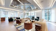 Located in the heart of Philadelphia's Center City at 1607 Sansom Street, this thoughtfully designed single-floor space offers a generous and versatile layout across its expansive footprint. The living area is a standout, showcasing a dramatic geometric ceiling treatment with metallic paneling and integrated linear lighting that adds architectural depth and visual interest. Floor-to-ceiling windows line the perimeter, flooding the space with natural light and offering open views of the surrounding cityscape. The living area is divided into distinct seating zones furnished with a mix of neutral sofas, teal wingback chairs, and rich velvet swivel seats in warm burgundy tones, all anchored by striped hardwood flooring. A secondary lounge area features a large sectional sofa and a round pedestal coffee table, framed by sheer floor-length curtains. The kitchen is equally impressive, outfitted with rich walnut cabinetry, a dramatic marble slab backsplash, stainless steel appliances, and a substantial stone-topped island with bar seating. A separate entertainment room features bold teal paneled walls, warm hardwood floors, a pool table, foosball table, and a stylish pendant-lit dining area, making it ideal for social gatherings.