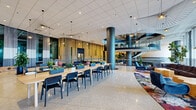 Located at 800 S Wells St in Chicago's South Loop, this single-floor space showcases a thoughtfully designed, contemporary interior that balances open communal areas with defined private zones. The polished terrazzo flooring extends throughout, reflecting light and reinforcing a sense of expansive, fluid movement across the space.

A sweeping curved staircase serves as a dramatic architectural centerpiece, framed by vertical wood slat wall panels and living green installations that introduce warmth and biophilic elements. Large, glass-walled meeting and conference rooms line one corridor, offering transparency and views into the main floor while maintaining acoustic separation.

The open lounge areas feature bold, eclectic furnishings—including modular sofas, velvet accent chairs, and vibrant botanical-patterned rugs—set beneath striking wire pendant light fixtures. A long communal worktable with planters runs through the central gathering zone, ideal for collaborative use. Floor-to-ceiling windows along the perimeter admit abundant natural light and frame views of the surrounding cityscape.

A standout reading nook features a dramatic arched alcove with a colorfully organized bookshelf wall and intimate seating. An open fitness area with glass partitions rounds out the diverse programming of this dynamic, amenity-driven floor.