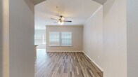 This single-floor residence offers a thoughtfully designed layout that balances functionality with comfort. The main living area features wood-look plank flooring that extends throughout much of the unit, complemented by crown molding and a ceiling fan with integrated lighting. Arched architectural accents add character, while built-in shelving units on either side of the archway provide practical display and storage options. Large windows fitted with white blinds invite abundant natural light into the living spaces.

The kitchen is well-equipped with light wood cabinetry offering generous storage, stainless steel appliances including a refrigerator, electric range, microwave, and dishwasher, and a granite-look countertop island that serves as a natural gathering point. Adjacent to the kitchen, a nook with open corner shelving offers additional organizational space.

The bedrooms feature plush carpeting, ceiling fans, and windows that allow for natural light, creating a comfortable and restful atmosphere. The bathroom is finished with clean white subway tile surrounding a full soaking tub and shower combination, accented by wood-look tile flooring that ties the space together cohesively.

Throughout the residence, neutral warm-gray wall tones create a versatile backdrop, and the overall design reflects a clean, modern aesthetic suited to a variety of living styles.