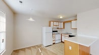 This single-floor, 2-bedroom, 2-bathroom residence features a practical and comfortable layout designed for everyday living. The kitchen is efficiently arranged in a U-shaped configuration, offering ample cabinetry with wood-trimmed white cabinets, a full suite of white appliances including a refrigerator and electric range, a black dishwasher, and a double-basin sink. A peninsula with a light countertop provides additional prep space, and a pendant light adds a finishing touch above the adjacent dining area, which transitions seamlessly into the living space. The open living area is bright and welcoming, featuring neutral carpet flooring, textured ceilings, and windows that allow natural light to filter through. Both bedrooms are generously sized, carpeted, and finished with neutral tones, offering a calm and versatile environment. One bedroom includes a ceiling fan with a light fixture and a window, adding both comfort and natural light. The two full bathrooms each feature a tub and shower combination with chrome fixtures and clean white surrounds, accompanied by tile flooring and vanity storage. The overall design is clean and understated, providing a move-in-ready living space with all essential amenities thoughtfully in place.