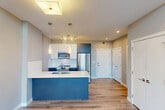 Located at 11303 105 Avenue NW in Edmonton, Alberta, this well-designed two-bedroom, two-bathroom residence offers a thoughtfully arranged single-floor layout with modern finishes throughout. Light wood-tone laminate flooring runs continuously through the main living areas, complementing the neutral grey and white colour palette that gives the space a clean, contemporary feel.

The open-concept kitchen is a standout feature, centred around a bold navy-blue island with a white quartz countertop and undermount sink. White upper cabinetry is paired with darker lower units, and the space is equipped with stainless steel appliances including a full-size refrigerator, microwave, and range. Stylish pendant lights and a track fixture illuminate the kitchen, which flows seamlessly into the living area. Large windows in the living room invite generous natural light and offer views of the surrounding neighbourhood.

The primary bedroom features a tray ceiling detail, laminate flooring, and a bright window, providing a comfortable and well-proportioned retreat. The second bedroom is similarly bright with its own window and light flooring. Both bathrooms are finished with large-format tile flooring, white fixtures, and contemporary vanities with undermount sinks. One bathroom includes a full soaker tub and shower combination. Additional conveniences include in-unit laundry and multiple closets for ample storage throughout.