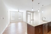 Located at 3955 Fair Ridge Dr in Fairfax, VA, this well-appointed 2-bedroom, 3-bathroom single-floor residence offers a thoughtfully designed layout with a bright, open feel throughout. The combined living, dining, and kitchen area forms the heart of the home, featuring light hardwood-style flooring, neutral tones, and abundant natural light streaming through multiple windows. A ceiling fan adds comfort to the spacious living area, which flows seamlessly toward a glass-paneled exterior door leading to the private patio.

The kitchen is a standout feature, boasting a large granite-topped island with a built-in sink and pendant lighting overhead. Rich dark-wood cabinetry lines the walls, complemented by stainless steel appliances including a refrigerator, range, and microwave. A tile backsplash adds a refined finishing touch.

Both bedrooms are generously sized, carpeted for warmth, and include ceiling fans and ample natural light. Each is served by well-appointed bathrooms featuring dark-wood vanities with granite countertops, large mirrors, and porcelain tile flooring. One bathroom includes a glass-enclosed walk-in shower with a built-in bench and grab bars. The residence also includes a laundry area, utility room, hallway, and two closets, offering excellent storage and everyday functionality.