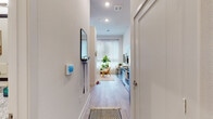 This single-floor unit offers a thoughtfully designed layout that seamlessly connects its key living spaces. An entry hallway, equipped with a wall-mounted mirror and hook rack, leads into the heart of the home, where light wood-style flooring runs throughout, creating a warm and cohesive feel.

The open-concept kitchen is fitted with rich dark-wood cabinetry, granite countertops, a subway tile backsplash, and a full suite of stainless steel appliances, including a dishwasher, range, microwave, and refrigerator. Adjacent to the kitchen, the combined dining and living area is bright and inviting, with tall windows dressed in sheer curtains that allow generous natural light to fill the space. The living area features notably tall ceilings that enhance the sense of openness.

The bathroom showcases dark wood vanity cabinetry with granite countertops, a large framed mirror, and light wood-style flooring that continues the unit's design language. The bedroom is complemented by a walk-in closet with built-in shelving and double hanging rods, providing ample storage. Throughout the unit, clean white walls and modern recessed lighting contribute to a bright, contemporary ambiance.