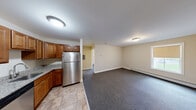 Located at 277 E Allen St in Winooski, Vermont, Unit 224 is a thoughtfully designed one-bedroom, one-bathroom residence that makes efficient use of its compact footprint. The open layout connects the kitchen and living area seamlessly, creating a functional and comfortable flow throughout the single-floor unit.

The kitchen is a standout feature, equipped with warm-toned wooden cabinetry, granite countertops, and a full suite of stainless steel appliances including a refrigerator, electric range, dishwasher, and built-in microwave hood. Tile flooring runs through the kitchen and entry area, providing a durable and easy-to-maintain surface.

The living area transitions to plush carpeting, offering a cozy atmosphere with a baseboard heating system to keep the space comfortable through Vermont winters. A wall-mounted mini-split unit provides additional climate control. Natural light enters through windows fitted with roller shades, with views of the surrounding greenery.

The bedroom is a well-proportioned private retreat, also carpeted, with a window overlooking the outdoors and baseboard heating. The bathroom features a full tub-shower combination with a handheld showerhead, set against neutral tiling and warm beige walls. The overall aesthetic throughout the unit is clean and neutral, offering a move-in-ready canvas.