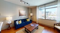 Located at 1551 Union Street in San Diego, CA, this single-floor residence offers a thoughtfully designed layout that balances style and functionality. The living area features warm hardwood flooring, track lighting, and large floor-to-ceiling windows that frame views of the surrounding cityscape, filling the space with abundant natural light. A bold navy sofa anchors the room alongside a rustic wood coffee table and curated wall art, creating an inviting and contemporary atmosphere.

The kitchen is well-equipped with rich cherry wood cabinetry, dark granite countertops, a stone tile backsplash, and a full suite of stainless steel appliances including a French door refrigerator, electric range with microwave, and dishwasher. A built-in wine rack adds a refined touch, while slate tile flooring ties the space together seamlessly.

The bedroom is a restful retreat, complete with plush carpeting, a ceiling fan, and a large window dressed with sheer curtains that allow soft natural light to filter in. The room offers generous space for a king-sized bed and additional furnishings.

The bathroom features dark granite countertops atop cherry wood vanity cabinetry, a large mirror, slate tile flooring, and a full soaking tub with stone tile surround. Every detail of this residence reflects a commitment to comfort and quality finishes throughout.
