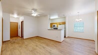This two-story residence is designed with a practical, open layout that maximizes usability across both levels. The main floor centers on a combined living and dining area finished with light wood-style flooring and ceiling fans, creating a bright, airy atmosphere enhanced by natural light from multiple windows. A chandelier accents the dining space, while a front entry door with paneled detailing provides a welcoming arrival point.

The kitchen is positioned behind a half-wall peninsula featuring granite-style countertops, offering a natural division from the living area without sacrificing openness. Warm honey-toned cabinetry lines the kitchen walls, complemented by white appliances including a coil-burner range, over-the-range microwave, and full-size refrigerator. Wood-style flooring continues throughout the kitchen.

A staircase leads to the upper level, where the bedrooms are located. One bedroom features plush carpeting, a ceiling fan, and a window with blinds for natural light. Another bedroom offers wood-style flooring and a sliding-door closet with built-in shelving. Two bathrooms serve the residence — one includes a vanity with warm wood cabinetry and a tub-shower combo, while the second features an extended vanity with ample counter space and a walk-in shower.
