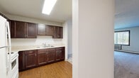 Located at 3755 Hubbard Ave N in Robbinsdale, Minnesota, this one-bedroom, one-bathroom unit offers a practical and comfortable single-floor layout. The combined kitchen and living room serves as the heart of the home, with the kitchen showcasing rich dark-stained wood cabinetry, light countertops, wood-look laminate flooring, and white appliances including a refrigerator and range. The open layout allows the kitchen to flow naturally into the living area, which features plush carpeting, a ceiling fan with light fixture, baseboard heating, and a window with vertical blinds that brings in natural light. The spacious primary bedroom is generously sized, offering soft carpeting, a full-width sliding double closet, baseboard heating, and a large window overlooking the outdoors. A connecting hallway lined with neutral tones and warm wood-tone doors links the rooms cohesively. The bathroom is clean and functional, featuring a full soaking tub with a tiled surround. Throughout the unit, textured ceilings and neutral wall tones create a simple, understated ambiance that provides a versatile canvas for personalization.