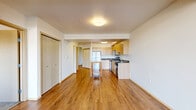 Located at 4040 26th Avenue Southwest in Seattle, WA, this well-appointed two-bedroom, one-bathroom unit offers a thoughtfully designed single-floor layout. Warm hardwood-style flooring flows throughout the main living areas, anchoring the open-concept space that combines the living room, dining area, and kitchen into one cohesive, light-filled zone. Large floor-to-ceiling windows in the living area frame scenic outdoor views and flood the space with natural light.

The kitchen is outfitted with light wood cabinetry, stainless steel appliances including a refrigerator, range, microwave, and dishwasher, and a generous countertop island that provides additional prep and dining space. An in-unit stacked washer and dryer is conveniently tucked near the kitchen entry.

Both bedrooms feature plush carpet, ample natural light, and outdoor views through sizeable windows. A dedicated den adds flexible space suitable for a home office or additional lounge area. The bathroom includes a walk-in glass shower, wood-toned vanity, and hardwood-style flooring. Five closets throughout the unit ensure abundant storage. A private balcony extends the living space outdoors, offering elevated views of the surrounding Seattle neighborhood.