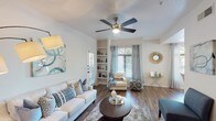 Located at 3636 E Inverness Ave in Mesa, Arizona, this single-floor residence offers a well-organized layout with thoughtfully designed living spaces throughout. The living room serves as the heart of the home, featuring vaulted ceilings, dark hardwood-style flooring, a ceiling fan with light fixture, and built-in shelving. Multiple windows dressed with light teal curtains and wood blinds allow generous natural light to fill the space. Adjacent to the living area, a dedicated dining nook stands out with a distinctive octagonal tray ceiling, a pendant light fixture, and a bay window arrangement that brings in abundant outdoor light. The kitchen is outfitted with two-tone cabinetry — grey lower cabinets paired with white uppers — white countertops, stainless steel appliances including a range, microwave, and dishwasher, and a window above the sink. The bedrooms each include ceiling fans, plush carpeting, and closet space. The full bathroom features wood-look flooring, a wide white vanity with an extended mirror, and a shower with a curtain enclosure. A dedicated laundry area houses a full-size washer and dryer with overhead shelving. The overall ambiance is clean, bright, and move-in ready.