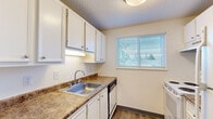 This single-floor, 3-bedroom, 1-bathroom unit offers a well-organized and efficient layout designed for comfortable everyday living. The main living area features wood-look flooring and a ceiling fan with a built-in light fixture, creating a bright and airy atmosphere. A sliding glass door allows natural light to pour in and provides direct access to an outdoor area, extending the sense of space.

The kitchen is outfitted with white cabinetry, laminate countertops, a stainless steel sink, a dishwasher, and a range. A window above the counter brings in natural light, while the wood-look flooring ties the space together cleanly.

Each of the three bedrooms is carpeted and features individual windows dressed with blinds, offering natural light and outdoor views of surrounding greenery. Baseboard heaters are present throughout the bedrooms for reliable climate control. Each bedroom is equipped with a closet, including sliding-door closets with built-in shelving and hanging rods for organized storage.

The bathroom includes a single vanity with a mirror cabinet, wood-look flooring, and a bathtub. A textured ceiling is consistent throughout the unit, lending a uniform character to every room. Overall, the space is clean, functional, and well-suited for efficient residential living.