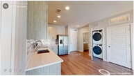Located in Raleigh, NC, this well-designed two-bedroom, two-bathroom residence offers a cohesive modern aesthetic across its single floor. Warm wood-look flooring flows seamlessly throughout every room, creating a clean, unified foundation for the contemporary design.

The kitchen is a standout feature, outfitted with light wood cabinetry, quartz countertops, a subway tile backsplash, and a full suite of stainless steel appliances including a French door refrigerator with water dispenser, electric range, built-in microwave, and dishwasher. A stacked washer and dryer unit is conveniently integrated near the kitchen, adding practical in-unit laundry access.

The primary bedroom offers a generous footprint with a ceiling fan, a large window that brings in natural light and outdoor views of the surrounding landscape. The second bedroom similarly benefits from a bright, oversized window with scenic views and neutral toned walls. Both rooms are served by their own bathrooms, each featuring textured wood-finish vanities, white quartz countertops, and large mirrors. The primary bath connects directly to a dedicated walk-in closet with wire shelving. A second closet provides additional storage. Recessed lighting, clean white trim, and neutral gray walls contribute to the overall light and airy ambiance of this thoughtfully finished residence.