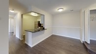 This single-floor residence offers a well-organized layout with a clear separation between living, dining, and sleeping areas. The main living space is finished with dark hardwood-style flooring and neutral gray walls, creating a clean, modern atmosphere. A raised-panel entry door anchors the entryway, which flows openly into the living and dining areas.

The kitchen is accessible via a peninsula that doubles as a breakfast bar, featuring dark granite countertops and an undermount sink. Inside the kitchen, white cabinetry provides generous storage, while stainless steel appliances — including an electric range, over-the-range microwave, and dishwasher — complete the functional setup.

The bedrooms are carpeted in a warm beige tone and are illuminated by windows fitted with horizontal blinds that allow for natural light and outdoor views. One bedroom features access to a walk-in closet equipped with dual wire shelving systems on both sides, offering ample organized storage. An additional doorway from one bedroom reveals in-unit laundry facilities nearby.

The bathrooms include a full tub and shower combination with white tile surrounds and chrome fixtures. One bathroom features dark hardwood-style flooring, a vanity, and a curved shower curtain rod, contributing to the overall cohesive, neutral aesthetic throughout the residence.