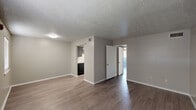 Located at 4020 Highway 365 in Port Arthur, Texas, this single-floor, 2-bedroom, 1-bathroom unit offers a practical and well-organized layout. The open living area greets you at the front entrance, featuring durable wood-look laminate flooring, neutral gray walls, and a textured ceiling that runs throughout the unit. Two windows flank the entry door, allowing natural light to fill the space.

The kitchen is efficiently designed in a galley style, equipped with gray cabinetry, light speckled countertops, a white refrigerator, and a white electric range. A ceiling vent provides ventilation, keeping the kitchen comfortable during use.

The primary bedroom is a generously sized room featuring a ceiling fan, a sliding glass door with vertical blinds that invites natural light, and direct access to the outdoors. The second bedroom is a comfortable, well-lit space with a window fitted with blinds and an adjacent closet for storage.

The bathroom is clean and functional, offering a full tiled tub-shower combo, a toilet, and a vanity with a speckled countertop, all finished with the same wood-look flooring found throughout the unit.

Overall, this unit presents a cohesive, move-in-ready interior with consistent finishes and a straightforward, efficient floor plan.