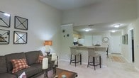 Located at 312 Foxtail Dr. in Pataskala, Ohio, this single-floor residence offers a thoughtfully designed open-concept layout that promotes a sense of spaciousness and easy flow between living areas. The living room is warm and inviting, featuring soaring ceilings that enhance the airy atmosphere and neutral-toned walls that lend a clean, versatile backdrop for any décor style. Soft carpeting underfoot adds comfort to the space. Transitioning seamlessly from the living area, the kitchen is positioned at an elevated counter height, anchored by a breakfast bar with bar-height seating — ideal for casual dining or entertaining. The kitchen is outfitted with light wood cabinetry, white appliances, and ample counter space, reflecting a functional and practical design. The open pass-through between the kitchen and living room ensures the spaces feel connected while maintaining distinct zones. Throughout the home, the neutral color palette, consistent flooring, and clean architectural lines create a cohesive and welcoming ambiance. The single-story layout offers convenience and accessibility, making this Pataskala home a comfortable and well-appointed residence.