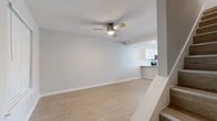 This well-designed one-bedroom, one-bathroom unit offers a practical and comfortable single-floor layout with consistent wood-look flooring flowing throughout every room, creating a cohesive and easy-to-maintain living environment. The living area is bright and open, featuring a ceiling fan with light fixture and a pass-through window connecting to the kitchen, enhancing the sense of openness between spaces. A full-size black refrigerator anchors the kitchen transition area, which is a standout feature of the unit. The kitchen itself is thoughtfully updated with white shaker-style cabinetry, granite countertops, a mosaic tile backsplash in neutral tones, and a full suite of stainless steel appliances including an electric range, over-the-range microwave, and dishwasher. Recessed lighting illuminates the kitchen efficiently. The bedroom is a comfortable, well-proportioned retreat with its own ceiling fan, a window fitted with blinds for natural light and privacy, and clean white walls. The hallway provides a functional transition between rooms, leading to the full bathroom, which includes a tub/shower combination with white tile surround, a toilet, a vanity with white cabinetry, and wood-look flooring that maintains the unit's consistent aesthetic throughout.