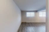 Located on Jamesville Avenue in Syracuse, NY, this one-bedroom, one-bathroom unit offers a practical and efficiently organized single-floor layout. The living room is the largest area of the unit, featuring durable grey wood-style plank flooring, neutral light grey walls, and two windows fitted with horizontal blinds that allow natural light to fill the space. A baseboard heating system runs along the exterior walls throughout the unit, ensuring consistent warmth. The bedroom is a cozy, private space with its own window and baseboard heater, maintaining the same flooring and clean aesthetic found throughout. The kitchen is equipped with white cabinetry offering ample upper and lower storage, light speckled countertops, a stainless steel sink, and under-cabinet lighting. The bathroom includes a full tub and shower combination with a curtain rod and brushed nickel fixtures. A dedicated vanity area with a lighted mirror and built-in shelf is conveniently located adjacent to two closets, providing functional storage solutions. The entrance leads smoothly into the main living area, giving the unit a logical and accessible flow. Overall, the space presents a clean, move-in ready environment with consistent finishes throughout.