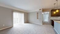 Located at Worthington Woods in Columbus, Ohio, this single-floor, 2-bedroom, 1-bathroom home offers a comfortable and functional layout with a neutral color palette throughout. The open-concept living and dining area is spacious and carpeted, featuring a sliding glass door with vertical blinds that floods the room with natural light and provides access to an outdoor balcony. A decorative wall niche adds a subtle architectural detail to the shared living space. The kitchen is well-appointed with rich, dark wood cabinetry, granite-style countertops, a white subway tile backsplash, and black appliances including a refrigerator, range, and over-the-range microwave, all complemented by wood-look flooring. Both bedrooms are carpeted and generously sized, with the primary bedroom offering ample room for furnishings. The home includes four closets, providing excellent storage capacity, with wire shelving systems maximizing organization. A dedicated in-unit laundry room houses a full-size washer and dryer and features additional overhead wire shelving. The utility room and hallway round out the efficient floor plan, making this a well-organized and practical home in a convenient Columbus location.