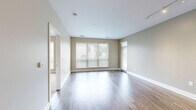 This thoughtfully designed 2-bedroom, 2-bathroom residence offers a comfortable and functional single-floor layout. The open-concept living and kitchen area serves as the heart of the home, featuring sleek wood-look luxury vinyl plank flooring that extends throughout the main spaces. The modern kitchen is outfitted with light wood cabinetry, white quartz countertops, stainless steel appliances including a refrigerator and dishwasher, and pendant lighting over a generous island — ideal for both cooking and casual dining. The spacious living room is bathed in natural light through large windows with horizontal blinds and offers direct access to a private outdoor balcony, enhancing the sense of openness. Both bedrooms are carpeted for comfort, with neutral warm-toned walls and ample natural light. The generously sized primary bedroom includes a dedicated walk-in closet outfitted with wire shelving systems on multiple walls, providing excellent storage capacity. The bathrooms feature tile flooring, wood-toned vanity cabinetry, white countertops, large mirrors, and a glass-enclosed walk-in shower. Clean lines, neutral finishes, and a cohesive design palette give this residence a contemporary and move-in-ready appeal throughout.