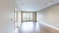 This thoughtfully designed 2-bedroom, 2-bathroom residence offers a comfortable and functional single-floor layout. The open-concept living and kitchen area serves as the heart of the home, featuring sleek wood-look luxury vinyl plank flooring that extends throughout the main spaces. The modern kitchen is outfitted with light wood cabinetry, white quartz countertops, stainless steel appliances including a refrigerator and dishwasher, and pendant lighting over a generous island — ideal for both cooking and casual dining. The spacious living room is bathed in natural light through large windows with horizontal blinds and offers direct access to a private outdoor balcony, enhancing the sense of openness. Both bedrooms are carpeted for comfort, with neutral warm-toned walls and ample natural light. The generously sized primary bedroom includes a dedicated walk-in closet outfitted with wire shelving systems on multiple walls, providing excellent storage capacity. The bathrooms feature tile flooring, wood-toned vanity cabinetry, white countertops, large mirrors, and a glass-enclosed walk-in shower. Clean lines, neutral finishes, and a cohesive design palette give this residence a contemporary and move-in-ready appeal throughout.