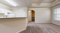 Located at 1027 Spring Creek Way in the Barcelona community of Douglasville, Georgia, this single-floor residence offers a thoughtfully designed layout that balances functionality and comfort throughout its interconnected living spaces.

The kitchen is outfitted with white cabinetry, granite-style countertops, and white appliances including a range, dishwasher, and refrigerator. Wood-look vinyl flooring anchors the kitchen and flows into adjacent areas, providing a durable and attractive surface. A breakfast bar peninsula separates the kitchen from the living area, creating an open and connected feel. Crown molding adds a refined architectural detail throughout.

The living area features plush carpet and opens through an elegant arched doorway into an alcove with built-in shelving, ideal for display or storage. The primary bedroom is distinguished by a tray ceiling with crown molding detail, a ceiling fan, and a door leading to an outdoor area, with ample natural light from multiple windows. Additional bedrooms are carpeted and include ceiling fans and windows overlooking surrounding greenery.

The bathroom features wood-look vinyl flooring, a white vanity with a stone-style countertop, and a tub-shower combination. Throughout the residence, neutral tones and consistent finishes create a cohesive and inviting atmosphere.