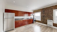 Located at 738 S New Hampshire Ave in the heart of Los Angeles, this single-floor studio offers a well-designed layout that maximizes every square foot. The combined kitchen and living area is the centerpiece of the space, showcasing a striking exposed brick accent wall with arched detailing that adds character and warmth. Two windows allow natural light to fill the room while offering views of the surrounding cityscape. The kitchen is outfitted with rich cherry wood cabinetry, granite countertops, a stainless steel gas range, and a full-size refrigerator — providing ample cooking and storage functionality. Light-toned hardwood flooring runs throughout the unit, complementing the crisp white walls and decorative crown molding that lend a polished, classic feel. Recessed lighting illuminates the space cleanly and efficiently. A dedicated closet with built-in shelving provides organized storage. The bathroom is well-appointed with warm wood-toned tile walls and flooring, a soaking tub with shower, a pedestal sink, and a window that brings in natural light. Together, these features create a cohesive, comfortable living environment that blends historic architectural charm with modern finishes.