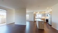 Located at 9800 Mira Lee Way in San Diego's Mira Mesa neighborhood, this single-floor residence showcases a thoughtfully designed open-concept layout with clean, contemporary finishes throughout. Rich dark hardwood flooring flows seamlessly through the main living and kitchen areas, creating a warm, cohesive aesthetic.

The kitchen is a standout feature, equipped with stainless steel appliances including a refrigerator, range, microwave, and dishwasher. Two-tone cabinetry pairs warm wood lower cabinets with light gray uppers, complemented by white quartz countertops and a subway tile backsplash. A central island with pendant lighting above adds both functionality and style. Natural light pours in through multiple windows, and a sliding glass door opens to a private outdoor balcony.

The bedrooms are finished with plush carpet and ceiling fans, offering a comfortable retreat. One bedroom features mirrored sliding closet doors. Both bathrooms are finished with large-format light tile flooring, wood-toned vanity cabinetry, white quartz countertops, and full tub-shower combinations. Recessed lighting and large mirrors complete the clean, modern look.

The spacious living area benefits from an open sightline to the kitchen and outdoor views, making the space feel bright and airy throughout.