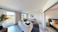 Located in the vibrant University District of Seattle, this contemporary single-floor residence at 4906 25th Ave NE offers a thoughtfully designed living experience. The open living area is bathed in natural light, courtesy of large floor-to-ceiling windows and a glass balcony door that frames treetop views of the surrounding neighborhood. Light hardwood-style flooring flows throughout, complementing the clean white walls and creating a bright, airy ambiance. A wall-mounted mini-split system ensures year-round climate comfort. The galley-style kitchen is efficiently laid out, featuring dark wood cabinetry, white countertops, a classic subway tile backsplash, and a full suite of stainless steel appliances, including a refrigerator, range, and microwave. The bedroom is a calm retreat, finished with soft neutral tones and featuring a frosted-glass sliding door that opens to a well-organized walk-in closet with built-in shelving and hanging space. The bathroom is clean and modern, offering warm wood-toned cabinetry, a white countertop vanity, and tile flooring. Throughout the residence, recessed lighting and a minimalist design aesthetic create a cohesive, contemporary feel that suits both everyday living and stylish entertaining.