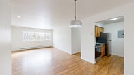 Located at 587 Broadway in Watervliet, NY, this two-bedroom, one-bathroom residence offers a well-organized single-floor layout with a clean, bright aesthetic throughout. Warm hardwood-style flooring runs continuously through every room, creating a cohesive and inviting atmosphere.

The open living area is bathed in natural light from a large multi-pane window, complemented by recessed lighting and a stylish pendant fixture. Baseboard heating runs along the perimeter, ensuring year-round comfort. The space flows seamlessly into the galley-style kitchen, which is equipped with warm wood cabinetry, granite countertops, a subway tile backsplash, and stainless steel appliances including a range, dishwasher, and refrigerator.

The primary bedroom is generously sized, featuring a wide bank of louvered sliding closet doors that provide abundant storage. The second bedroom includes its own window with outdoor views and baseboard heating. Three closets are distributed throughout the unit, offering exceptional storage capacity.

The bathroom is neatly appointed with a white vanity featuring shaker-style cabinetry, a mirror, and a separate shower/tub alcove with crisp white finishes. A connecting hallway ties all rooms together efficiently. Recessed lighting and white walls throughout lend the entire residence a fresh, move-in-ready feel.