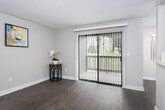 This single-floor residence offers a well-organized layout with several distinct living areas. The living room serves as a central gathering space, highlighted by a brick fireplace with a dark mantle and durable wood-look flooring that extends throughout the main areas. Neutral-toned walls and a textured ceiling contribute to a clean, understated aesthetic.

The kitchen features dark cabinetry with ample storage, light countertops, and a recessed tray ceiling with pendant lighting, lending a modern feel to the functional galley-style layout. It is equipped with a gas range and refrigerator, with enough counter space for comfortable meal preparation.

The bedroom is carpeted and benefits from natural light through a large window fitted with vertical blinds. A baseboard heater runs along the wall, ensuring year-round comfort. The bathroom includes a full tub-shower combination with clean white surrounds, wood-look flooring, and a towel bar for convenience.

A sliding glass door in the main living area opens to a balcony, offering outdoor views and additional natural light. Throughout the unit, consistent finishes and a cohesive color palette create a practical and comfortable living environment.