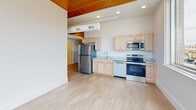 Located at 509 9th St in De Witt, Iowa, this distinctive 2-bedroom, 1-bathroom unit offers a compelling blend of historic character and modern updates. One of the most striking features upon entry is an original heavy-duty bank vault door, a nod to the building's storied past, complemented by ornate architectural moldings and warm wood ceiling panels that lend a sense of craftsmanship throughout.

The kitchen is outfitted with light maple cabinetry, stainless steel appliances including a refrigerator, range, microwave, and dishwasher, and light vinyl plank flooring that extends into the main living areas. The open layout allows natural light to flow freely, enhanced by oversized windows that frame views of the surrounding De Witt streetscape.

The primary bedroom features plush carpeting, a sliding-door closet, an additional storage closet, and warm wood ceiling detailing, with large windows that fill the room with natural light and outdoor views. The second bedroom is clean and minimal with light wood flooring. The bathroom includes a full soaking tub and shower combination with neutral tile flooring and modern chrome fixtures. This unit offers an informative glimpse into a thoughtfully converted historic commercial building.
