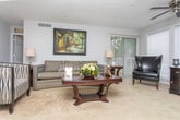 Located at 6907 Tara Blvd in Jonesboro, Georgia, this single-floor residence offers a well-organized layout designed for comfortable everyday living. The living room is a welcoming centerpiece, featuring a decorative textured ceiling, ceiling fan, and multiple windows that flood the space with natural light. Neutral-toned carpeting and light gray walls create a calm, cohesive atmosphere throughout.

The galley-style kitchen is efficiently designed with warm oak cabinetry, wood-look flooring, white appliances including a gas range, and ample counter space. A folding-door closet provides convenient pantry or storage access. Adjacent to the kitchen, the dining area features hardwood flooring and a pendant light fixture, offering a defined space for meals and gatherings.

The primary bedroom is generously sized with plush carpeting, a window for natural light, and a full dresser with mirror. A second bedroom also features carpet flooring and direct access to a walk-in closet. Both bathrooms are functional and well-appointed — one with warm wood-toned cabinetry and a tub/shower combination, and the other with white cabinetry, a large vanity mirror, and a shower. The overall ambiance is practical yet comfortable, making this a welcoming single-level home.