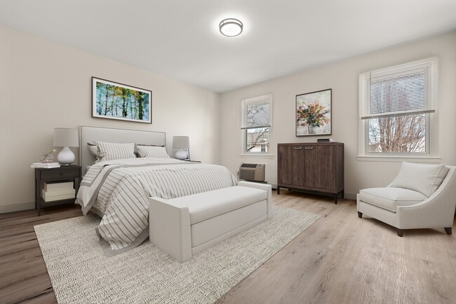 Habitación luminosa y elegante con una cama acogedora con sábanas a rayas, muebles modernos y grandes ventanales que dejan entrar luz natural. - Stony Brook Commons