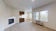 This well-appointed 2-bedroom, 1-bathroom unit at 1948 Linwood St NW in Salem, Oregon offers a thoughtfully designed single-floor layout. The galley-style kitchen is a standout feature, showcasing warm wood-tone cabinetry, white quartz countertops, stainless steel appliances including an electric range, built-in microwave, and refrigerator, all set atop light hardwood-style flooring. A peninsula with a curved white countertop provides additional prep space and a natural transition into the living area. The living room features plush neutral carpeting, a built-in fireplace, and access to a dedicated entry area with closet storage. Large windows in both the living room and bedrooms allow for ample natural light and outdoor views of the surrounding neighborhood. Both bedrooms are comfortably sized, carpeted, and include windows with blinds and wall-unit climate control. The primary bedroom offers a generous footprint with a built-in shelving unit and direct access to the shared bathroom. The bathroom is equipped with a dual-sink vanity, warm-toned wood cabinetry, a large wall mirror with overhead lighting, and hardwood-style flooring, providing both functionality and a clean, modern aesthetic throughout.